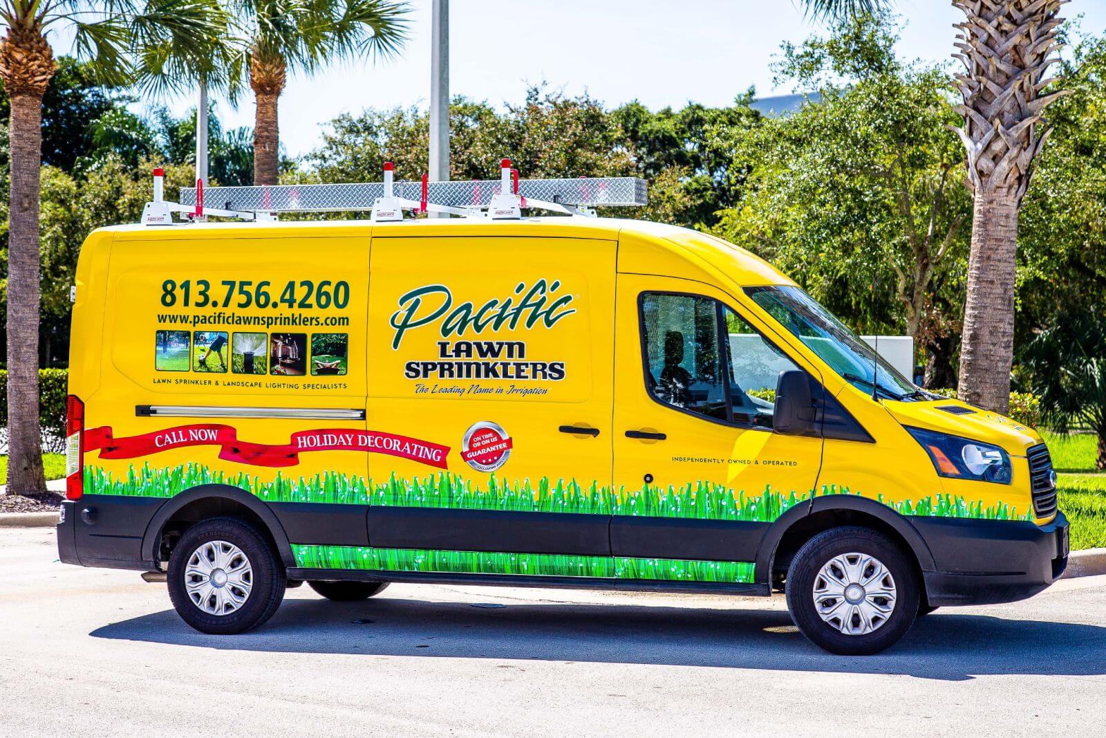 A yellow Pacific Lawn Sprinklers van parked outdoors, with contact information and service details printed on the side.